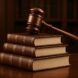 A wooden gavel placed on top of stacked law books in a library setting